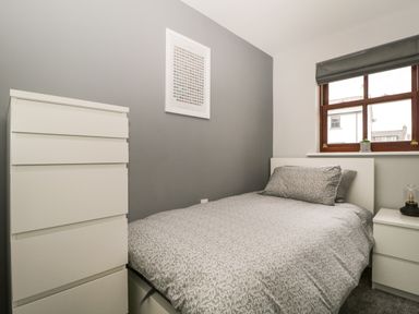 A bedroom with a bed a bedside table and a chest of drawers at Andra Ghyll in Keswick