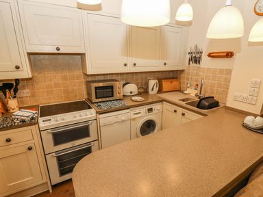 A kitchen with oven microwave dishwasher washing machine sink and countertop at Juniper Cottage in Ambleside