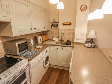 A kitchen with cabinets microwave stove washing machine sink and countertop at Juniper Cottage in Ambleside