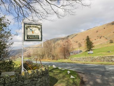 A road with a sign for Dale Head Hall Lakeside Hotel and Restaurant near hills and trees at The Hayloft in Thirlmere