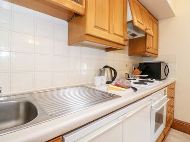A kitchen countertop with a sink kettle mugs bread cheese stove and microwave at The Hayloft in Thirlmere