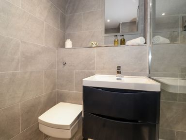A bathroom with a toilet a sink with a cabinet a mirror and toiletries at The Hayloft in Thirlmere