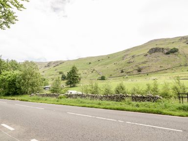 A rural road with stone wall and green fields with hills in the background at Thirlmere Suite in Thirlmere