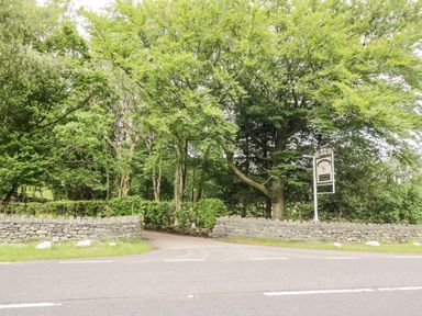 A road with stone walls and trees on both sides with a hotel and restaurant sign at Thirlmere Suite in Thirlmere