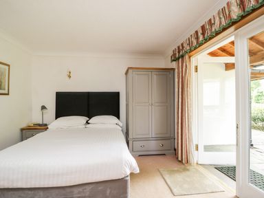 A bedroom with a bed a bedside table a wardrobe and glass doors leading outside at Thirlmere Suite in Thirlmere
