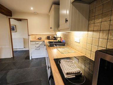 A kitchen with wooden countertops a stovetop with towels and cabinets at Scales Cottage in Lorton near Cockermouth