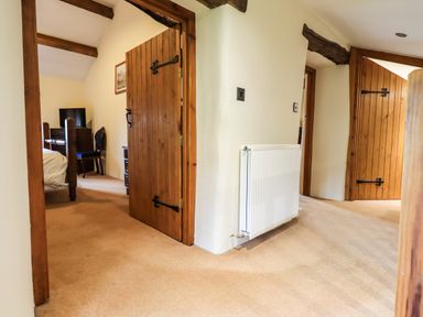 A hallway with carpeted floor wooden doors and a radiator at Scales Cottage in Lorton near Cockermouth