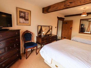 A bedroom with a bed dresser chair and a mirror at Scales Cottage in Lorton near Cockermouth