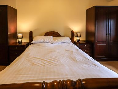 A bedroom with a double bed flanked by two bedside tables with lamps and two wardrobes at Scales Cottage in Lorton near Cockermouth