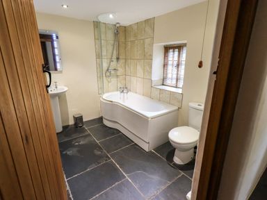 A bathroom with a bathtub shower toilet sink and a small window at Scales Cottage Lorton near Cockermouth