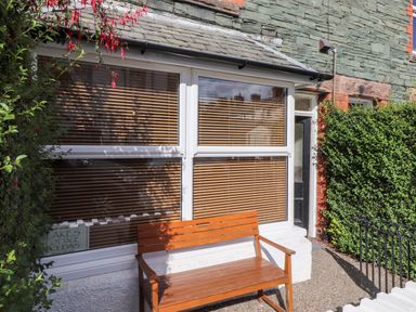 A wooden bench outside a window with closed blinds next to a black door at Archers in Keswick