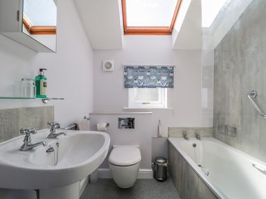 A bathroom with a sink toilet bathtub window with a sheep patterned blind and skylights at Swinside Cottage in Keswick