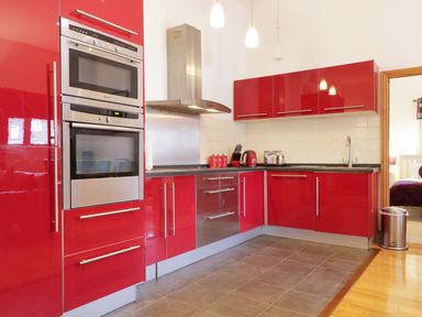 A kitchen with red cabinets stainless steel oven and appliances at Keswick Loft in Keswick