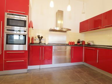 A kitchen with red cabinets stainless steel appliances and cooking utensils at Keswick Loft in Keswick