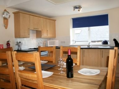 A kitchen with wooden dining table set with plates and wine bottle at Whitbarrow Holiday Village Troutbeck 5 in Ullswater