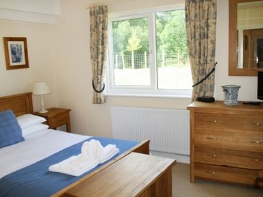 A bedroom with a bed side table lamp dresser and a window with curtains at Whitbarrow Holiday Village Troutbeck 5 Ullswater