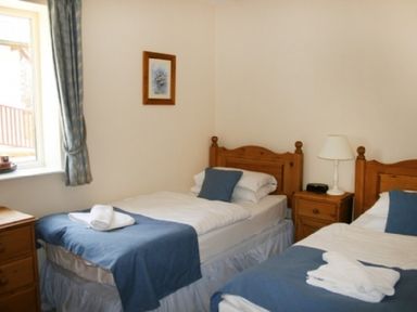 A bedroom with two single beds beside each other with blue bed runners and white bedskirts at Whitbarrow Holiday Village Troutbeck 5 Ullswater