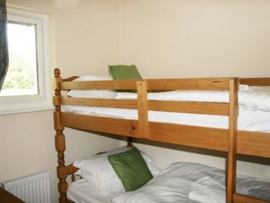 A bedroom with wooden bunk beds and green pillows at Whitbarrow Holiday Village Troutbeck 5 in Ullswater