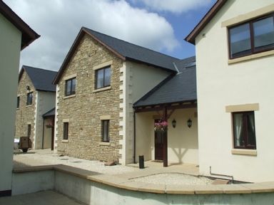 A courtyard with multiple two story buildings made of stone and plaster at Whitbarrow Holiday Village Troutbeck 5 Ullswater
