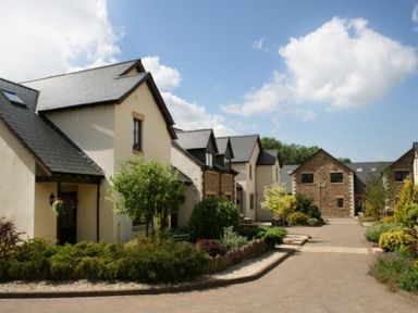 A row of residential buildings with garden shrubs and a paved walkway at Whitbarrow Holiday Village Troutbeck 5 Ullswater
