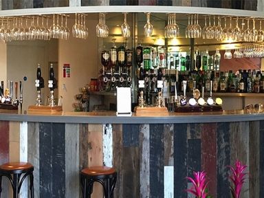 A bar counter with stools hanging glasses and bottles at Whitbarrow Holiday Village Troutbeck 5 Ullswater