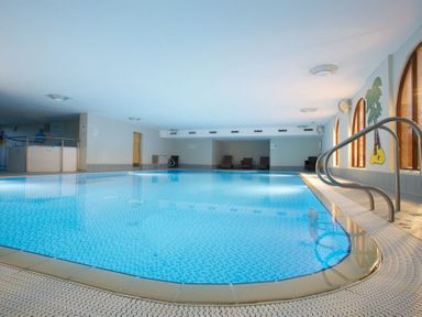 An indoor swimming pool with tiled floor metal handrails chairs against walls and windows at Whitbarrow Holiday Village Troutbeck 5 Ullswater