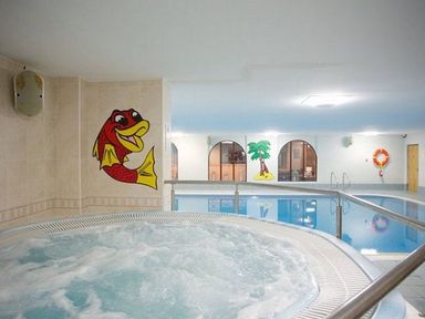 An indoor swimming pool area with a hot tub a fish mural and a palm tree mural on the wall at Whitbarrow Holiday Village Troutbeck 5 Ullswater