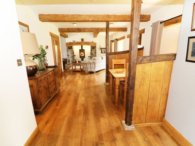A room with wooden floor beams sideboard and a sitting area with a fireplace at Grayrigg Foot Stable in Grayrigg
