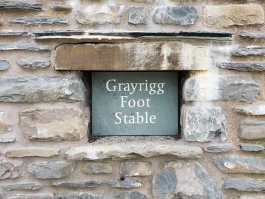 A stone wall with a plaque that reads Grayrigg Foot Stable in Grayrigg