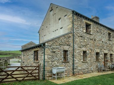 Stone house with multiple windows wooden gate and outdoor furniture at Grayrigg Foot Stable in Grayrigg