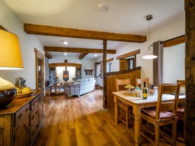 A living room and dining area with wooden furniture exposed beams and a fireplace at Grayrigg Foot Stable in Grayrigg