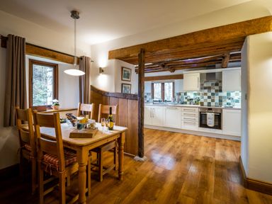 A kitchen and dining area with wooden table and chairs and white cabinets at Grayrigg Foot Stable in Grayrigg