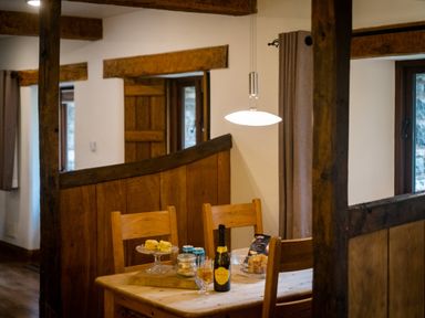 A wooden dining table with chairs and snacks on top in a room with wooden beams at Grayrigg Foot Stable in Grayrigg