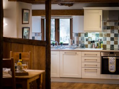 A kitchen with white cabinets a tiled backsplash and wooden beams at Grayrigg Foot Stable in Grayrigg