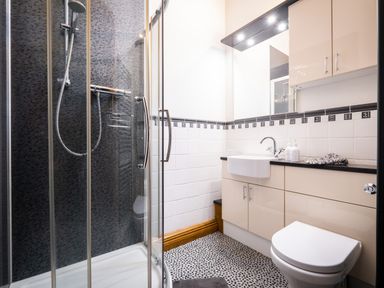 A bathroom with a shower, sink, toilet, cabinets, and a mirror at Grayrigg Foot Stable in Grayrigg