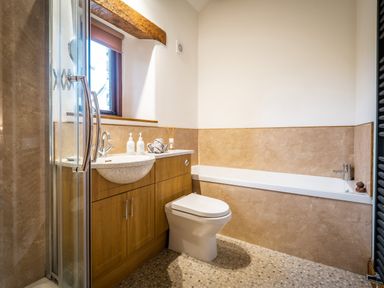 A bathroom with a toilet sink wooden cabinets bathtub and shower at Grayrigg Foot Stable in Grayrigg