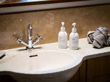 A bathroom sink with chrome faucet soap dispensers and rolled towels on a countertop at Grayrigg Foot Stable in Grayrigg