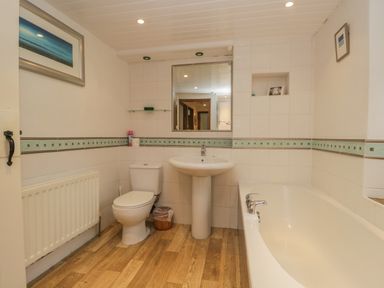 A bathroom with a toilet sink bathtub mirror and radiator at Tanner Croft Cottage in Grasmere