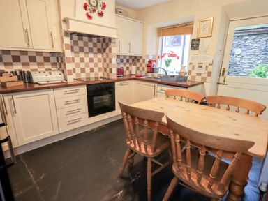 A kitchen with wooden table and chairs and tiled backsplash at Granary Nook in Windermere