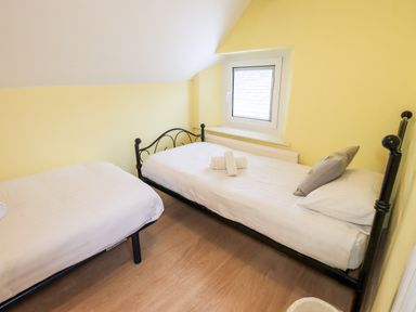 A bedroom with two single beds white bedding and a small window at Granary Nook in Windermere