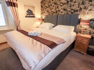 A bedroom with a double bed bedside tables lamps and a window at Granary Nook in Windermere