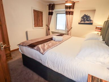 A bedroom with a bed towels on it a window with curtains and a lamp at Granary Nook in Windermere