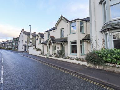 A street view of white painted houses with green window frames and small front gardens at Greta Mill in Keswick