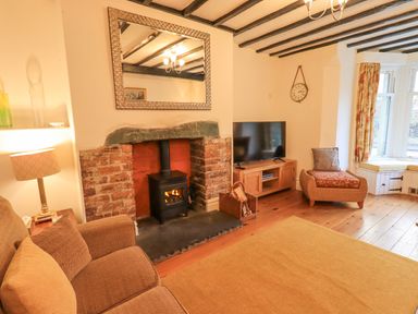 A living room with a fireplace tv armchair and window seat at Greta Mill in Keswick