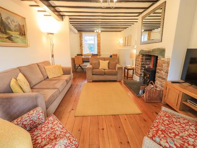 A living room with sofas chairs a fireplace and a dining table at Greta Mill in Keswick