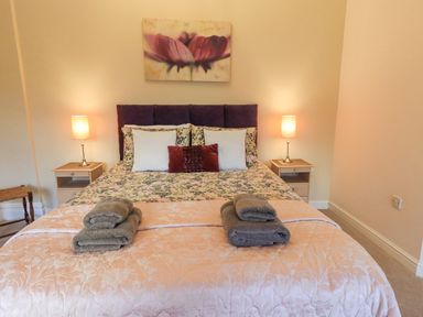 A bedroom with a double bed two bedside tables with lamps and folded towels at Greta Mill in Keswick