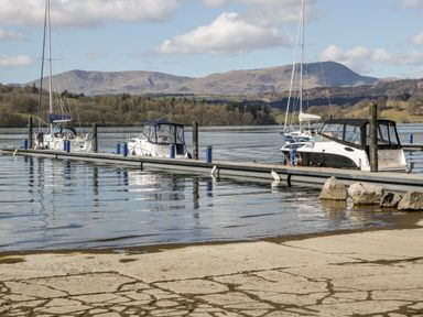 Boats docked at a marina with mountains and trees in the background at Tree Tops View in Bowness-On-Windermere