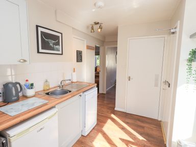 A kitchen with wooden floor a sink a kettle and a framed picture on the wall at Tree Tops View in Bowness-On-Windermere