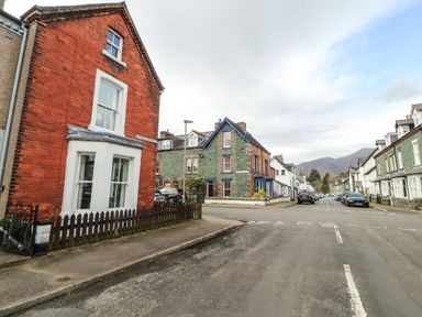 A street view with houses and parked cars on both sides under a cloudy sky at Pelham House in Keswick