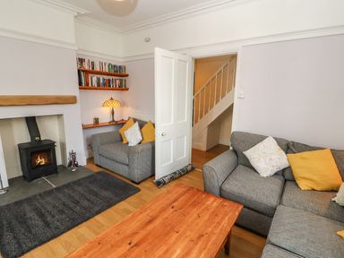 A living room with grey sofas and a wooden coffee table next to a fireplace with a wood-burning stove at Pelham House in Keswick